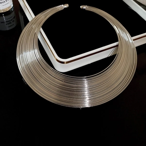 Close-up of a silver multi-layer wire necklace with metallic luster on black display