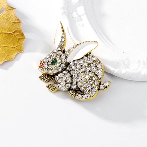 Gold rabbit brooch featuring sparkling diamonds and colorful enamel animal design