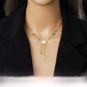 Close-up of gold tassel necklace featuring shell cloud, moon, and star pendants on model