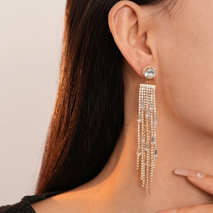 Close-up of elegant gold tassel earrings with glittering rhinestones on a model