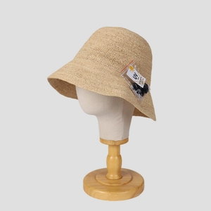 Detail of raffia bucket hat with UV care tag and adjustable clip on wooden stand