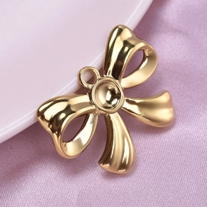 Detailed view of a shiny gold stainless steel bow pendant on elegant pink silk