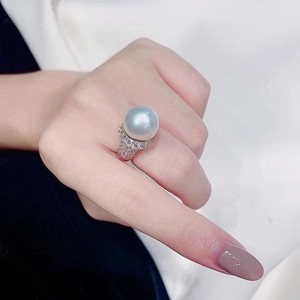 Detail van een grote barokke parelring met een zilveren band met diamanten op een model