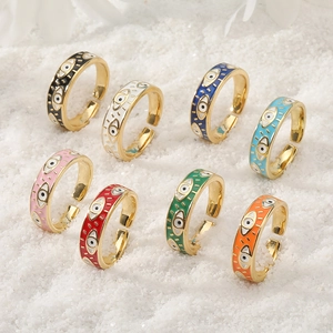 Adjustable evil eye rings set with colorful enamel finish on a sandy beach background