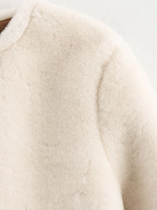 Détail de la texture en fausse fourrure et des coutures sur l'épaule d'une veste en peluche