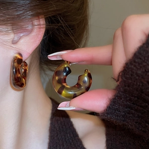 Detailed view of retro leopard print resin C-shaped earrings with glossy amber marble texture