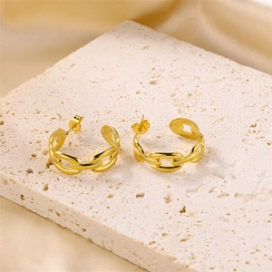 Macro view of gold chain-style hoop earrings on a textured stone surface
