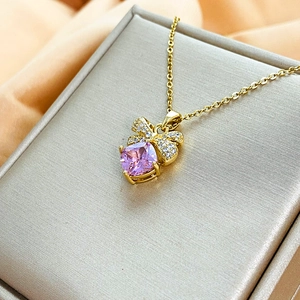Dettaglio collana fiocco oro con zircone viola e pavé di diamanti su portagioie