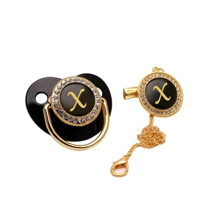 Detail of black and gold baby pacifier with rhinestone inlay and gold letter X engraving