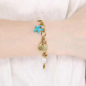 Détail du bracelet doré 18 carats avec breloques d'étoile de mer, coquillage et perles