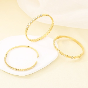 Trois élégants bracelets en acier titane doré avec cristaux étincelants sur support moderne
