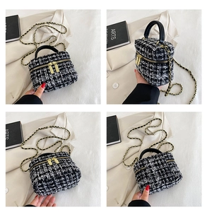 Detailweergave van stijlvolle zwart-witte tweed vanity tas met goudkleurige hardware en ketting