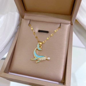 Close-up of dolphin pendant with blue enamel and pearl in a beige velvet jewelry box