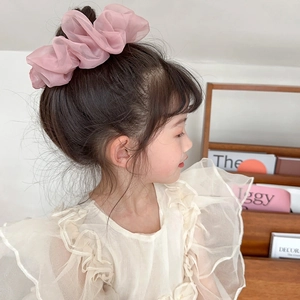 Pink oversized organza scrunchie shown on a ponytail in a soft home setting