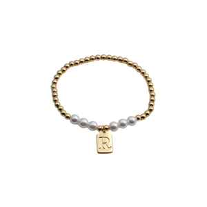 Detail of gold beaded bracelet with white pearls and a rectangular R letter charm