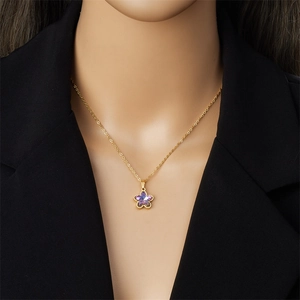 Elegant gold flower necklace with purple gemstone on model wearing a black blazer