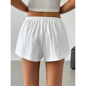 Detail view of white casual shorts with elastic waistband and pleated fabric texture