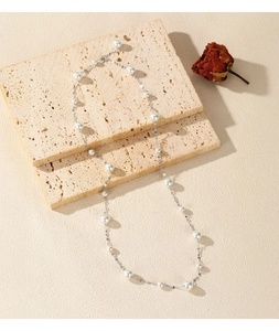 Detail view of silver S925 sterling silver necklace with white pearls on beige stone