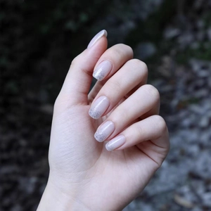 Close-up of pink and silver glitter gradient press-on nails with a glossy finish