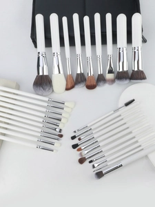 Overhead view of a professional 30-piece white and silver makeup brush set with a black bag