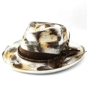 Close-up of a distressed white fedora hat featuring artistic graffiti and a real feather