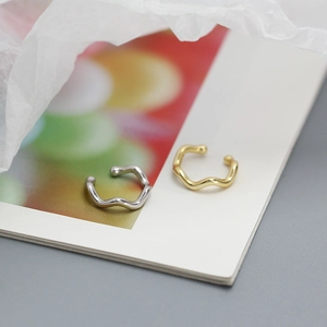 Macro shot of silver and gold wavy ear cuffs with sparkling stones on a magazine