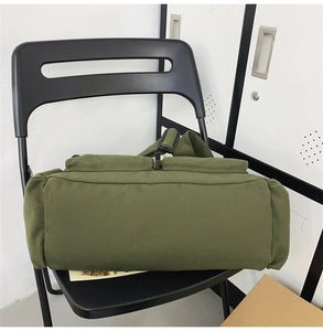 Detail of army green canvas shoulder bag with heavy texture on a black chair