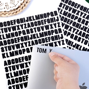 Close-up of black bold letter stickers being applied to a laptop for custom labeling