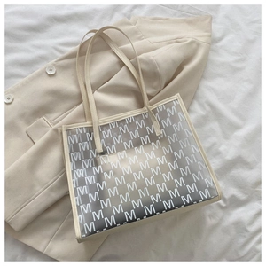 Macro detail of clear PVC tote bag with M-letter pattern and white leather strap