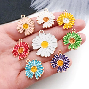 Macro detail of colorful enamel daisy charms with golden metal frames for DIY jewelry
