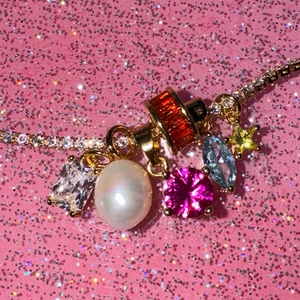 Sparkling gold tennis necklace featuring colorful gemstone charms and a large white pearl