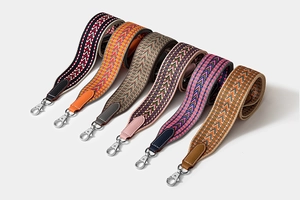 Macro detail of assorted woven herringbone shoulder straps with silver swivel metal hooks