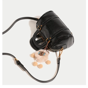 Close-up of black oil wax leather Boston bag with gold hardware and plush sheep charm