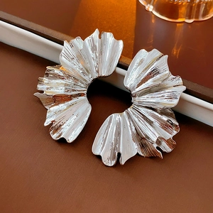 Detailed macro view of silver pleated fan-shaped earrings with artistic metal textures