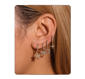 Detail of four gold plated earrings with flower, butterfly and cross zircon charms