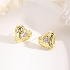 Macro view of gold-plated heart earrings with hammered texture and cubic zirconia stone
