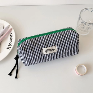 Detailed macro view of black and white checkered quilted pencil case with green zipper detail