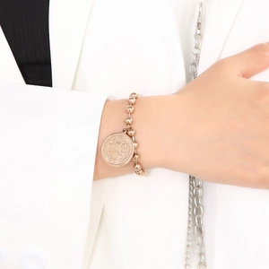 Close-up of Saint Benedict medal charm on golden ball chain bracelet worn by a model