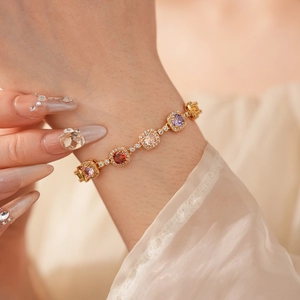 Detail of vintage gold bracelet featuring colorful zircon stones worn on a female wrist