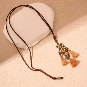Detail view of ethnic long necklace featuring floral metal parts and colorful tassels