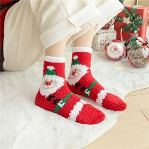 Festive Santa Claus coral fleece socks worn on feet with Christmas gift decorations