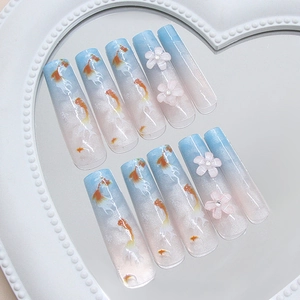 Blue gradient press-on nails with koi fish design and 3D flowers on a heart tray