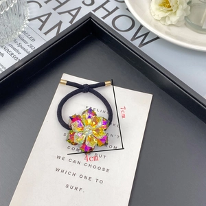 Detailed view of elastic hair tie with faceted crystal flower charm and gold metal closure