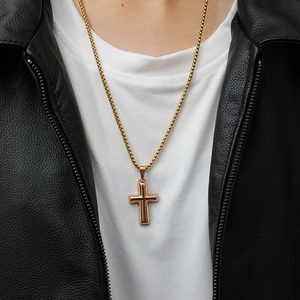 Close-up of a punk style gold stainless steel cross pendant necklace on a male model