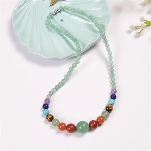 Detail of bohemian necklace with light green beads and multi-colored chakra stones on tray