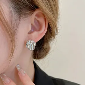 Silver wavy diamond stud earrings with irregular metallic texture for a minimalist style
