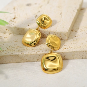 Macro view of golden geometric earrings on a beige stone surface with luxury lighting