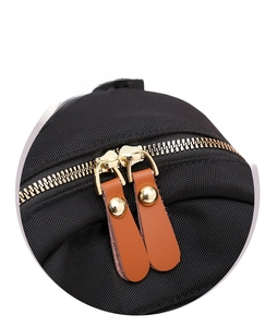 Detailed macro view of golden metal double zippers with brown leather pull tabs on a black bag