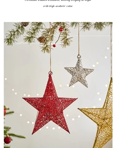 Close-up of glittery hollow star ornaments hanging on pine branches with warm bokeh lights