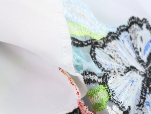 Dettaglio del ricamo floreale su tessuto mesh con eleganti cuciture blu e verdi